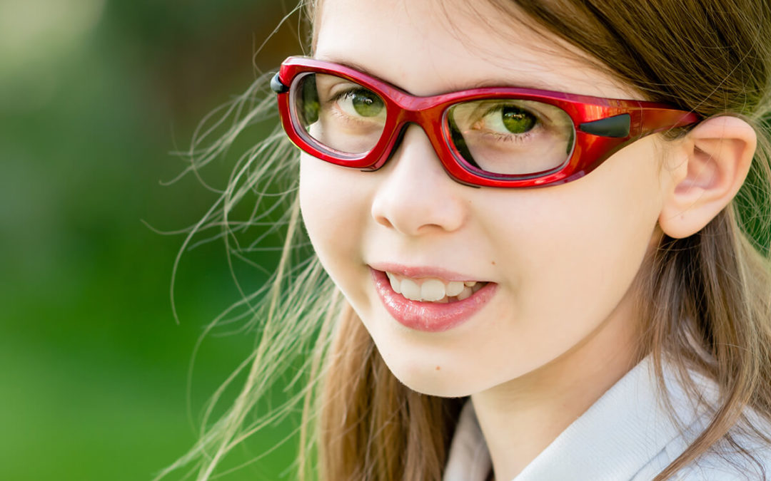 girl child wearing red prescription sports glasses